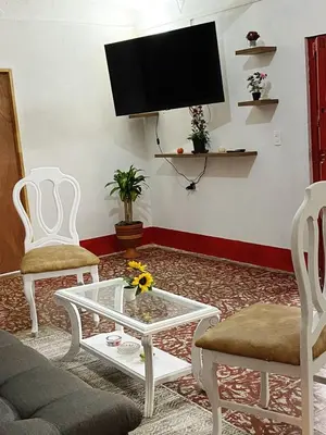 a living room with a tv and two chairs and a coffee table at Casa De Campo 