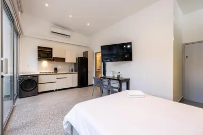a bedroom with a white bed and a kitchen at Contablers in Medellín