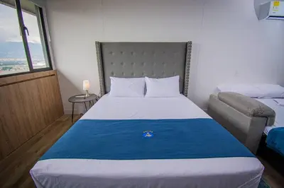 a bedroom with a large bed and a chair at TOP FLOOR Studio Poblado, A/C, Coworking, gym 1416 in Medellín
