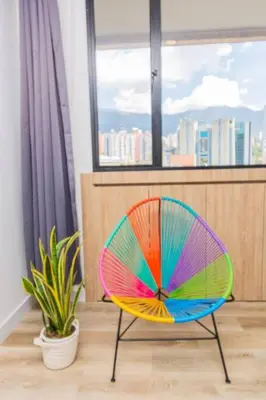 a colorful chair sitting in a room with a window at Poblado, Modern studio, coworking, A/C, Gym 1411 in Medellín