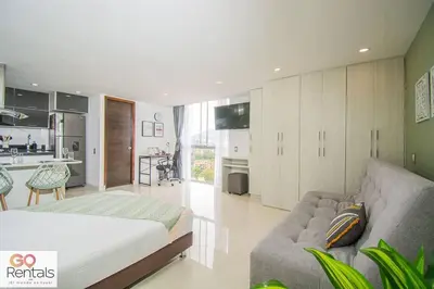 a bedroom with a bed and a couch and a kitchen at Cozy studio in Poblado, parking, NO FEE 1107 in Medellín