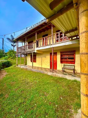 a yellow building with red doors and a grass yard at Wayra Ecolodge in El Peñol