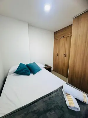 a bedroom with a large white bed with blue pillows at Grandioso apartaestudio muy cerca a Provenza 201 in Medellín