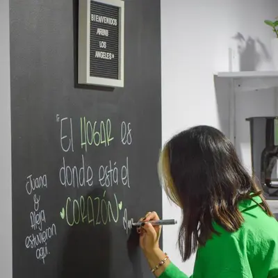 a woman writing on a chalkboard with a pen at Apartamento con tina para tu relax! Prime location in Manizales