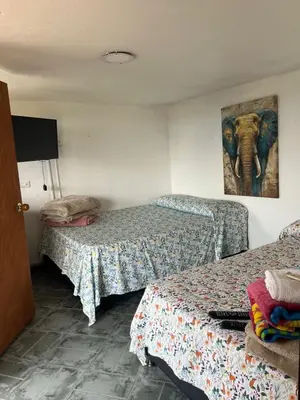 a room with two beds and a painting of an elephant at Hostal Inn II Rionegro in Rionegro