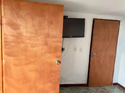 a room with a door and a television on the wall at Hostal Inn II Rionegro in Rionegro