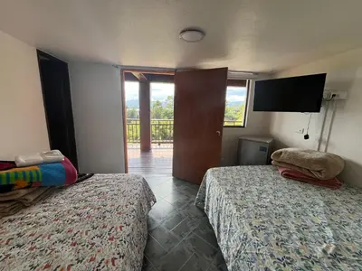 a bedroom with two beds and a door with a balcony at Hostal Inn II Rionegro in Rionegro