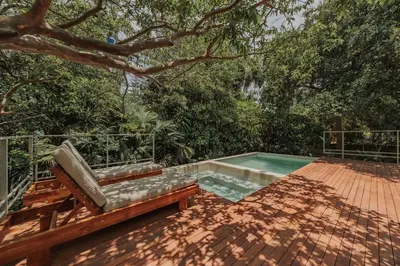 a pool with a bench on a deck with a tree at Casa Selva, a unique luxury house in the heart of El Poblado in Medellín