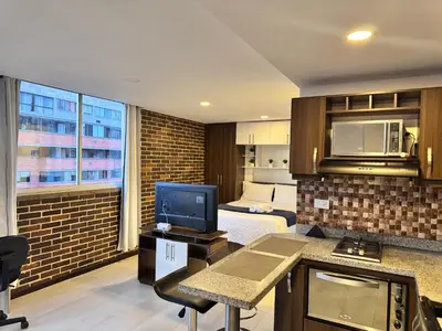 a room with a bed and a kitchen with a television at 2211 Despierta en poblado Medellín - Vista panorámica in Medellín