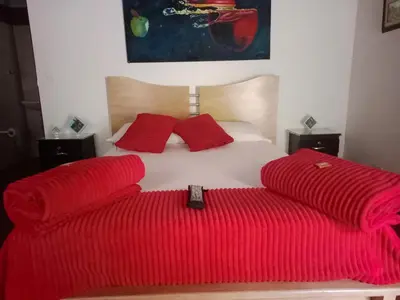a bed with red blankets and a remote control on it at Libélula finca-hotel in Concepción