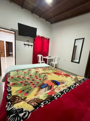 a bedroom with a large bed with a colorful blanket at Hotel Casa Azul in Sonsón