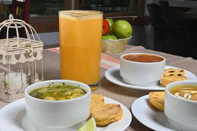 a table with a bowl of soup and a glass of juice at HOTEL PORTAL DE VITERBO Y RESTAURANTE LA FONDA in Viterbo