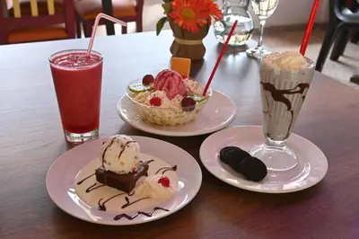 three plates of desserts on a table with two drinks at HOTEL PORTAL DE VITERBO Y RESTAURANTE LA FONDA in Viterbo