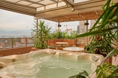 a jacuzzi tub on a balcony with plants at Hotel Dix in Medellín