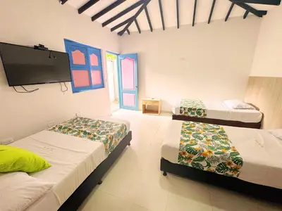 a room with two beds and a flat screen tv at Hotel Jardín Del Río in El Bosque