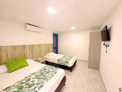 a hotel room with two beds and a tv at Hotel Jardín Del Río in El Bosque