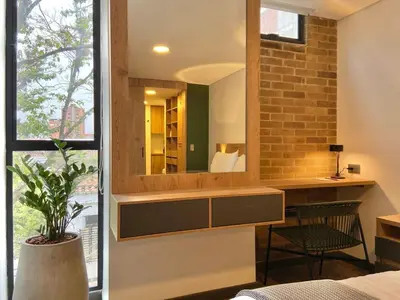 a bedroom with a mirror and a desk with a chair at Ganesh by Wynwood House in Medellín