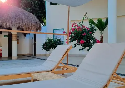 a couple of chairs and an umbrella and flowers at HOTEL SANTAFE NATURA - SANTAFE DE ANTIQUIA in Santa Fe de Antioquia