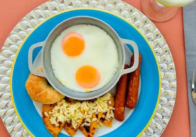 a plate of breakfast food with eggs and sausages at HOTEL SANTAFE NATURA - SANTAFE DE ANTIQUIA in Santa Fe de Antioquia