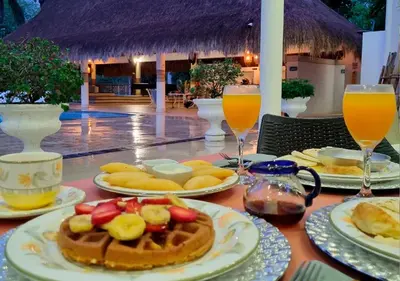 a table with plates of food and glasses of orange juice at HOTEL SANTAFE NATURA - SANTAFE DE ANTIQUIA in Santa Fe de Antioquia