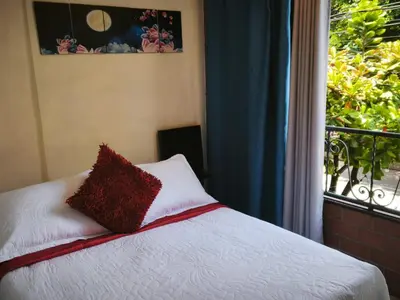 a bed with a red pillow and a window at Apartamento cerca a Medellín - Puerta del norte Bello in Machado