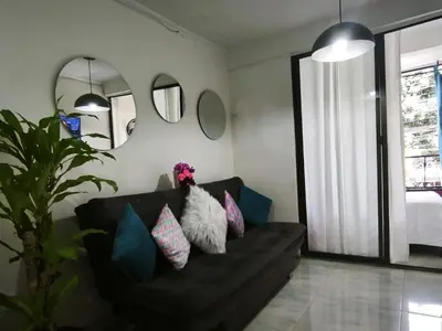 a living room with a black couch with pillows at Apartamento cerca a Medellín - Puerta del norte Bello in Machado