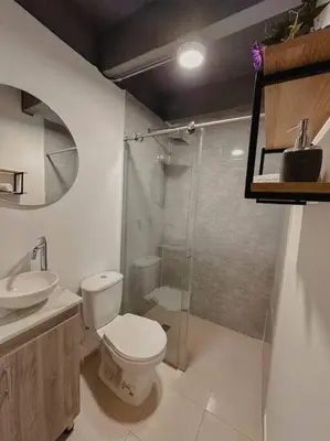 a bathroom with a toilet and a glass shower at Laureles Industry Living 4BR in Medellín
