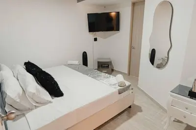 a bedroom with a bed with a tv on the wall at Laureles Industry Living 4BR in Medellín