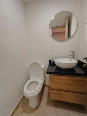 a bathroom with a toilet and a sink and a mirror at Laureles Industry Living 4BR in Medellín