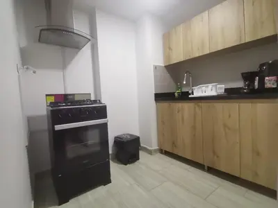 a kitchen with a black stove and wooden cabinets at Laureles Industry Living 4BR in Medellín
