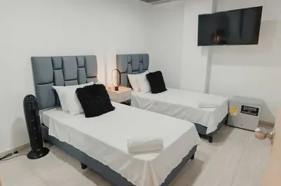 a room with two beds and a flat screen tv at Laureles Industry Living 4BR in Medellín