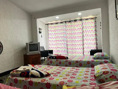 a bedroom with two beds and a tv in it at Hostal Monarca in Medellín