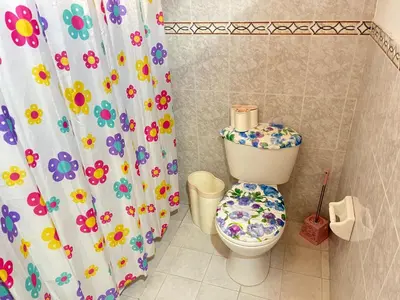 a bathroom with a toilet with a flower shower curtain at Hostal Monarca in Medellín