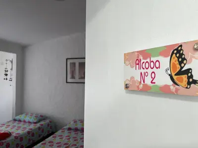 a room with a bed and a sign with a butterfly on the wall at Hostal Monarca in Medellín