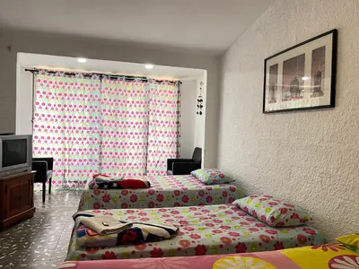 a room with two beds and a tv in it at Hostal Monarca in Medellín
