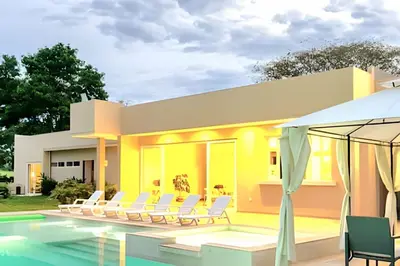a villa with a swimming pool with chairs and an umbrella at Mágica CASA FINCA de lujo piscina privada wi-fi tv in Mariquita