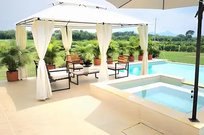 an outdoor swimming pool with an umbrella and a swimming pool at Mágica CASA FINCA de lujo piscina privada wi-fi tv in Mariquita