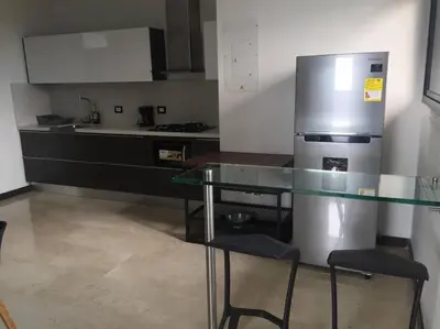 a kitchen with a glass table and a refrigerator at 2004 El Poblado cute and cozy apartment in Medellín
