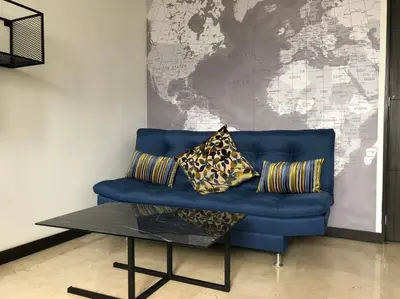 a blue couch with pillows and a table in front of a map at 2004 El Poblado cute and cozy apartment in Medellín