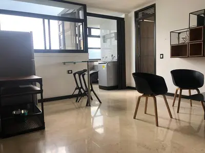 a living room with black chairs and a kitchen at 2004 El Poblado cute and cozy apartment in Medellín