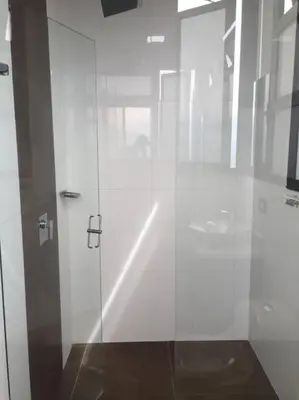 a white bathroom with a glass shower door at 2004 El Poblado cute and cozy apartment in Medellín