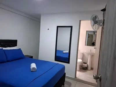 a bedroom with a blue bed and a bathroom with a mirror at Hospedaje Luna Llena in Manizales
