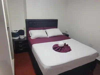 a bedroom with a bed with a white and purple blanket at Hospedaje Luna Llena in Manizales