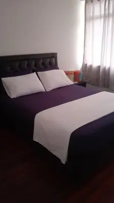 a bedroom with a large bed with white and purple sheets at Hospedaje Luna Llena in Manizales