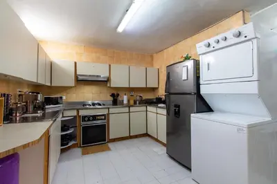 a kitchen with white cabinets and a black refrigerator at CoNomad House - Coliving & Coworking in Medellín