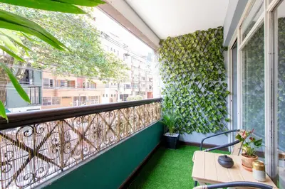 a balcony with green plants on the wall and a table at CoNomad House - Coliving & Coworking in Medellín
