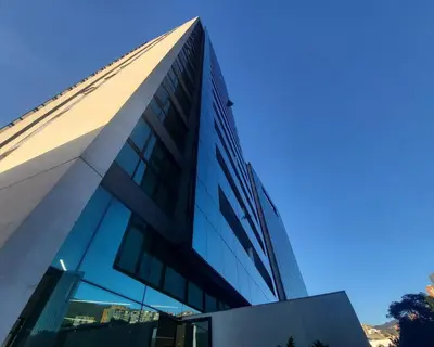 a tall glass building with a blue sky in the background at Luxury apt! Guest friendly! Great location! Jacuzzi, Gym, Security! in Medellín
