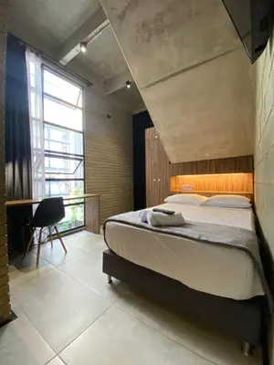 a bedroom with a bed and a chair and a window at Recinto68 in Medellín