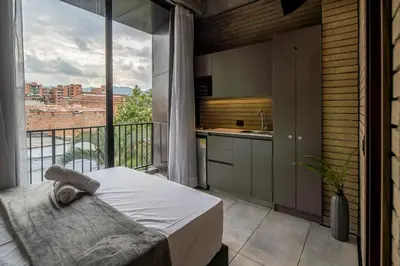 a bedroom with a balcony with a bed and a kitchen at Recinto68 in Medellín