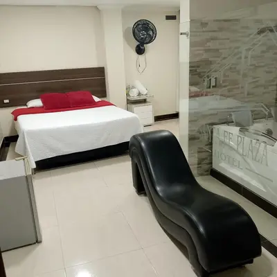 a bedroom with a bed and a black chair at Hotel santa fe plaza sucursal HBP in Santa Fe de Antioquia